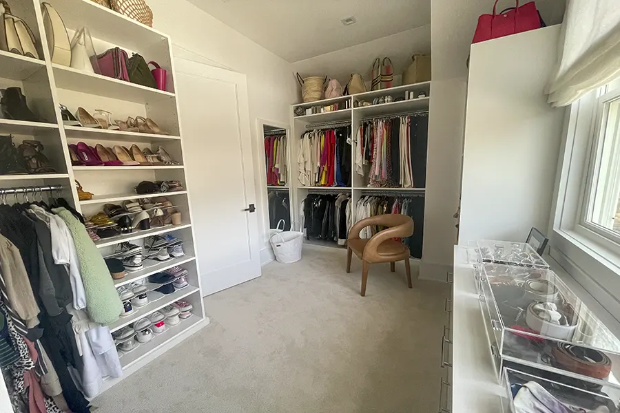 Custom walk-in closet featuring open shelving, shoe storage, hanging sections, accessory organization, and a seating area designed for everyday functionality.