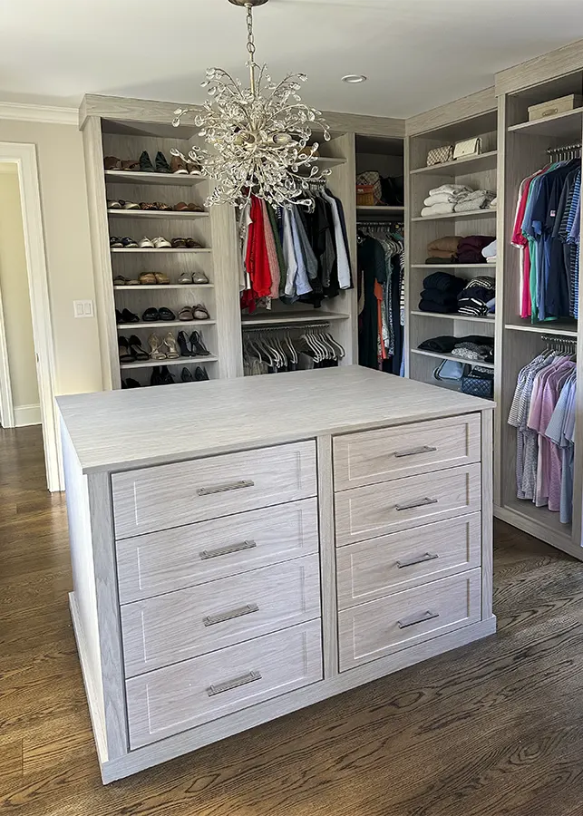 Custom walk-in closet with center island, hanging storage, shelving, and Weekend Getaway wood grain finish.