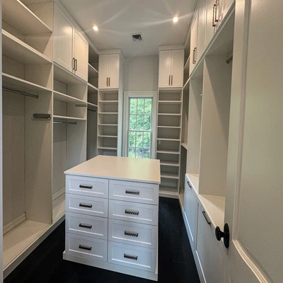 Custom white walk-in closet with central island, built-in shelving, and storage drawers